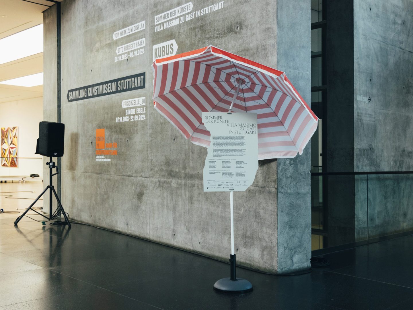 Striped beach umbrella with festival information used as on-site communication inside Kunstmuseum Stuttgart.