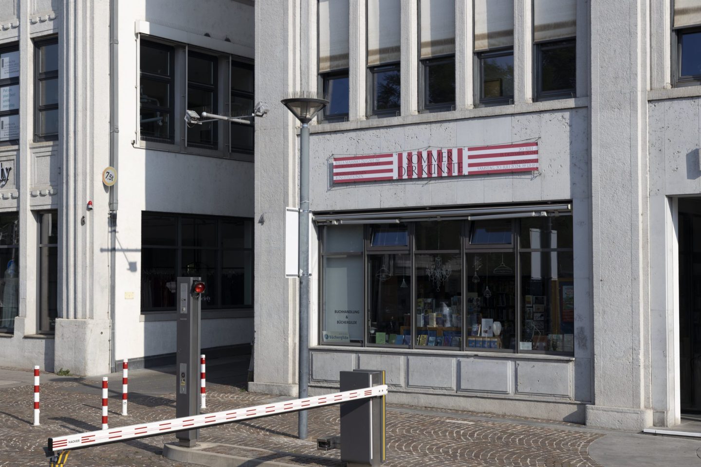 Striped Sommer der Künste banner mounted above a shopfront in Stuttgart.