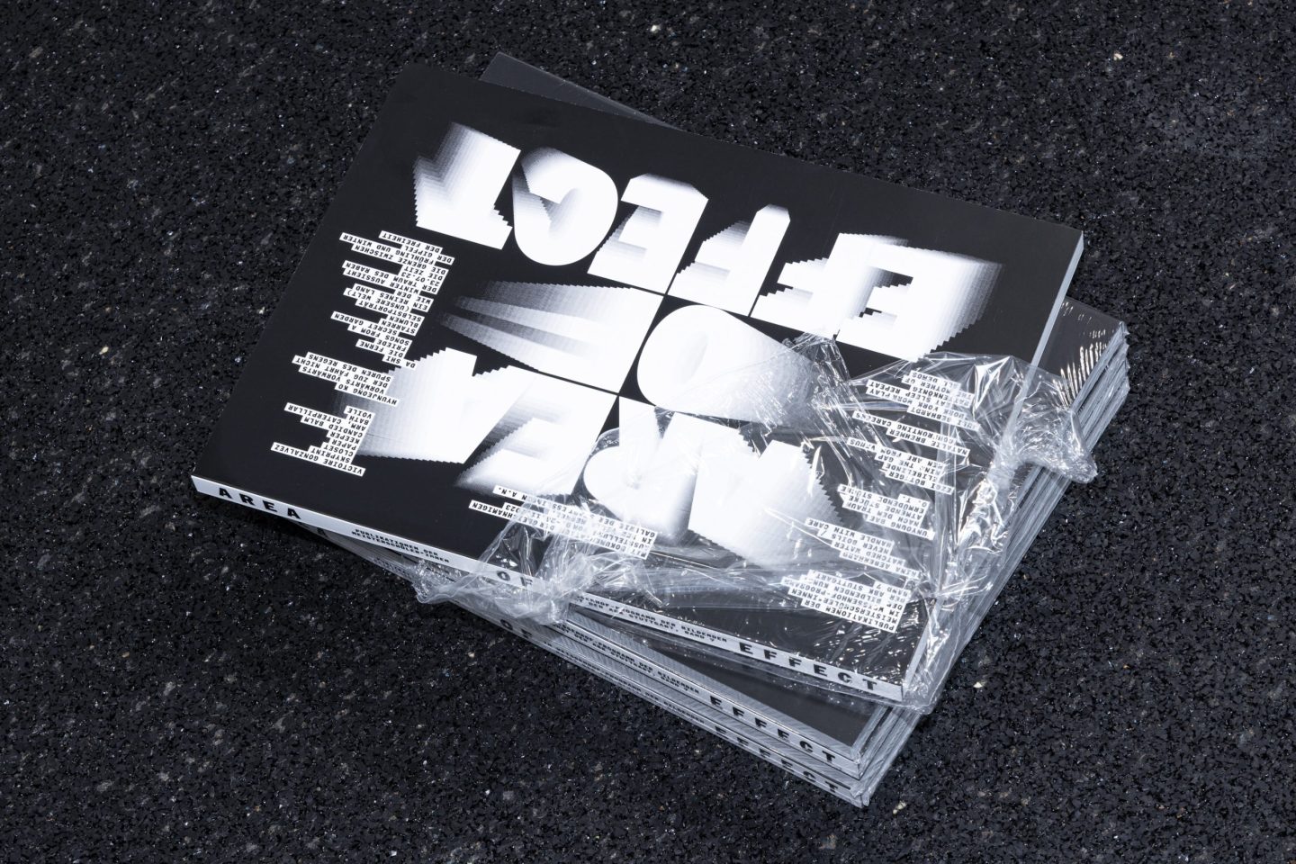 Catalogue design for the ABK Stuttgart Meisterschüler exhibition, featuring the publication Area of Effect with a black-and-white typographic cover and shrink-wrapped stacked copies.