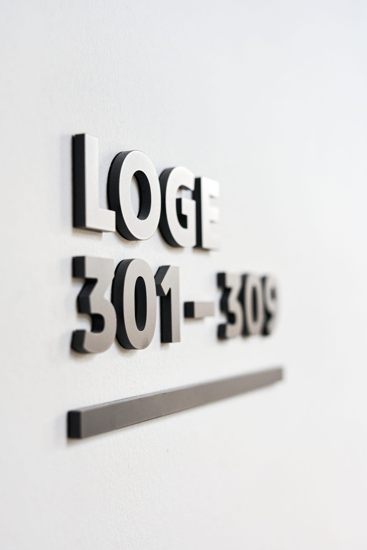 Wall signage for VfB Stuttgart at MHP Arena, featuring the destination name “Stöckach Platz” in dimensional lettering within a hospitality seating area.