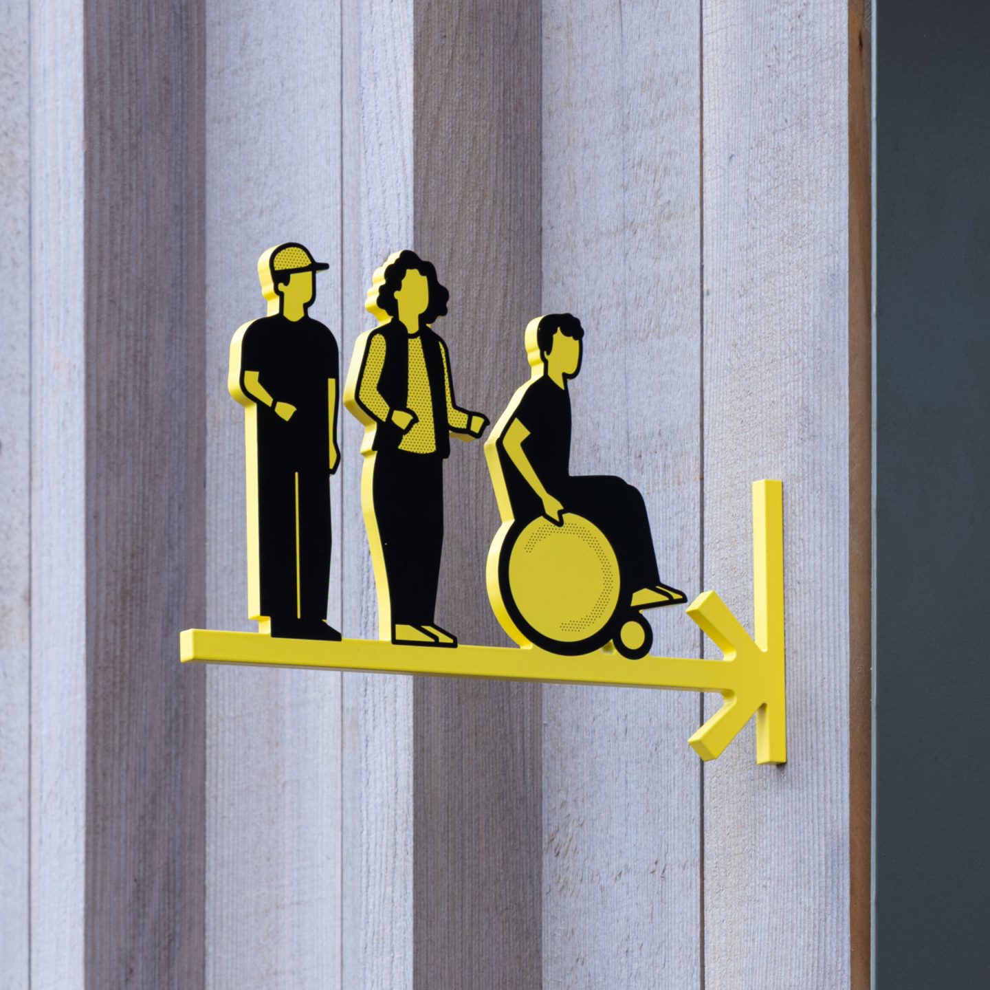 Pictogram design for Haus des Tourismus Stuttgart, featuring diverse visitor icons and an accessibility symbol on a projecting yellow wayfinding sign.