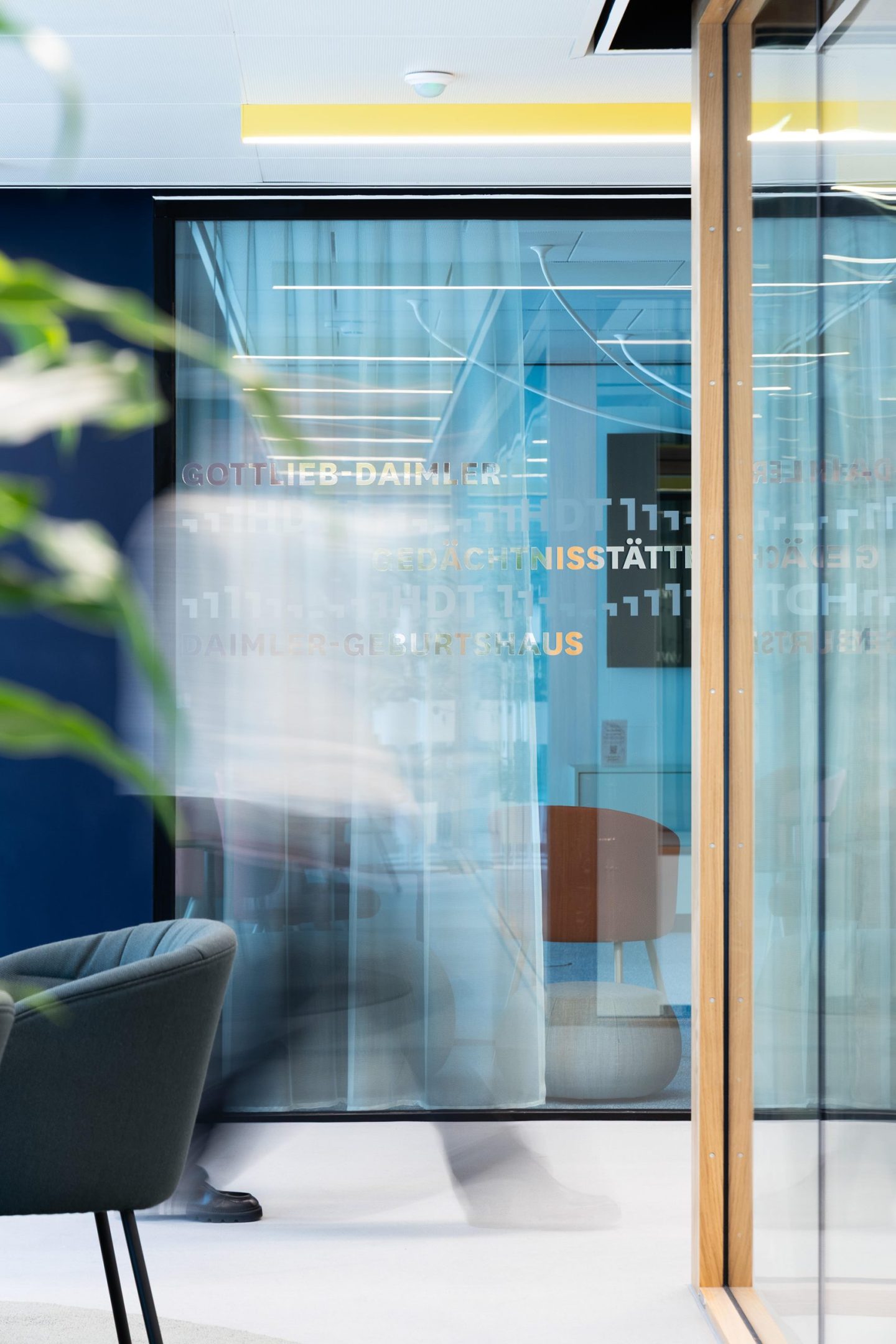 Interior wayfinding for Haus des Tourismus Stuttgart, featuring translucent glass signage with destination names integrated into a coworking and visitor space.