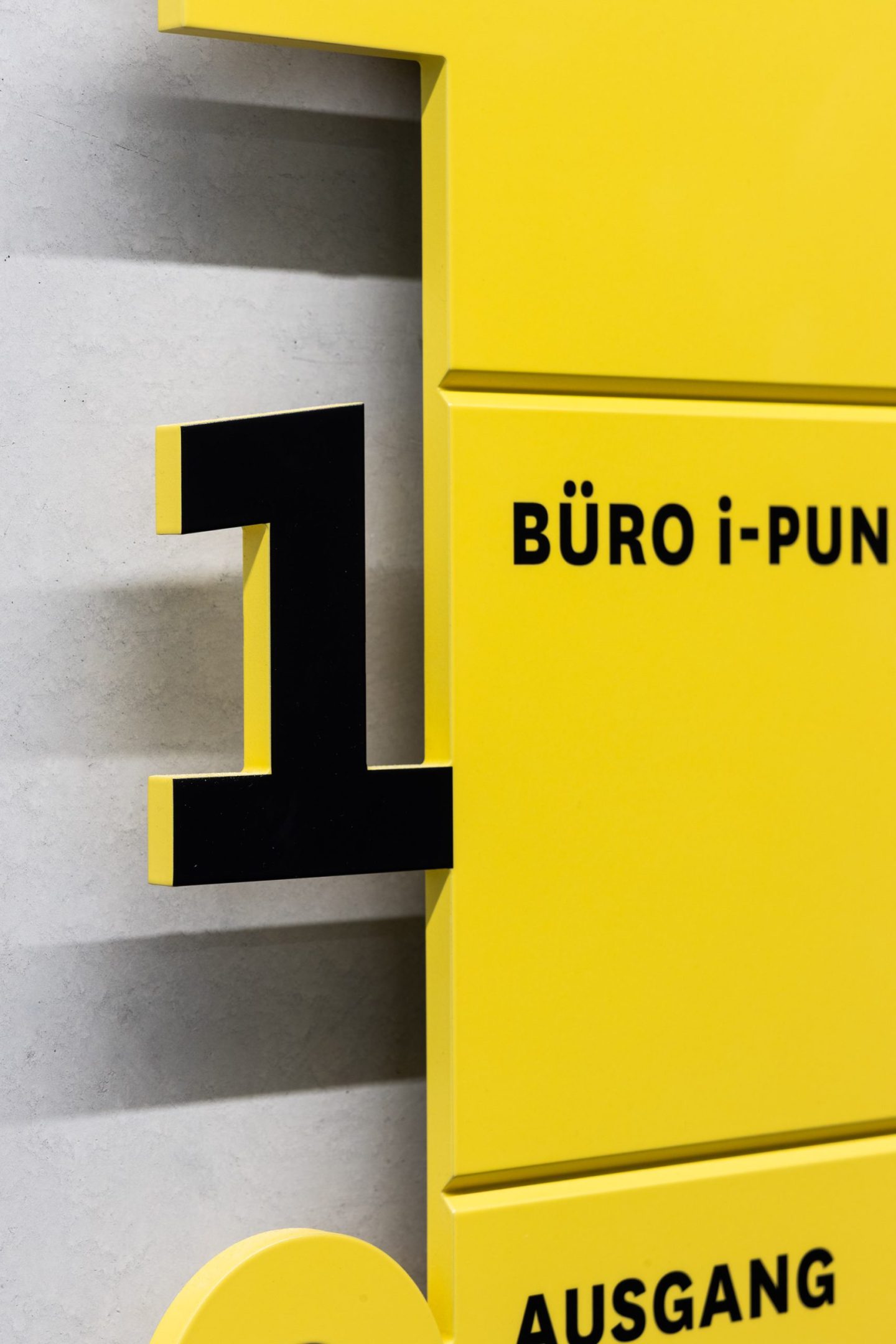 Stairwell wayfinding sign for Haus des Tourismus Stuttgart, featuring a large three-dimensional floor number and bold yellow directory panels with black destination typography.