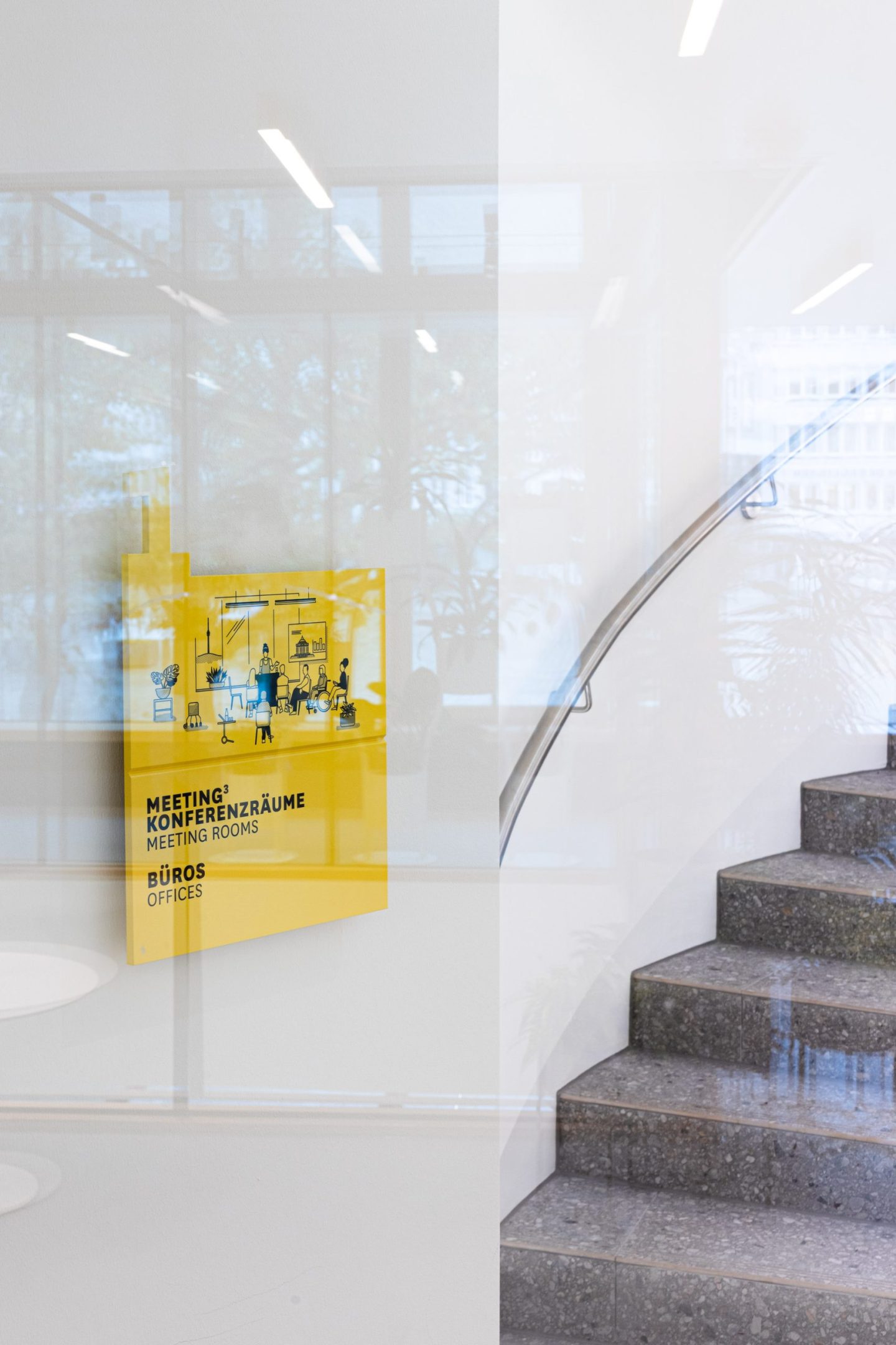 Interior wayfinding sign for Haus des Tourismus Stuttgart, featuring a yellow bilingual directory panel for meeting rooms and offices integrated into the stairwell orientation system.