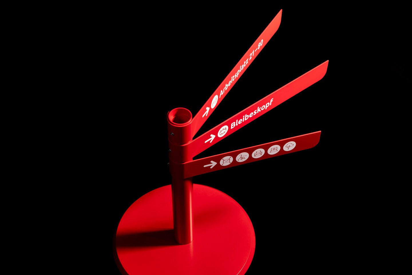 Wayfinding design for ALH Gruppe, featuring a red freestanding signpost with directional arrows, destination names and icon-based orientation.